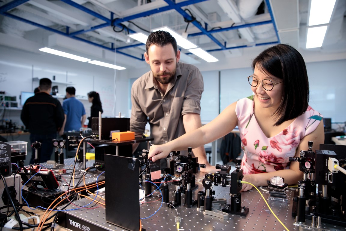 Two researchers working on equipment in the NUS-Singtel lab