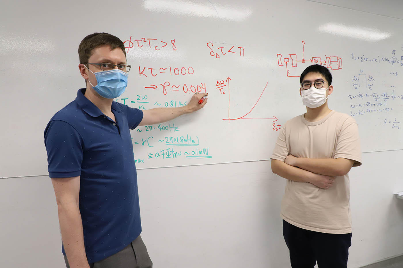 CQT Principal Investigator Travis Nicholson and PhD student Yu Xianquan pictured at a whiteboard with equations describing laser operations.