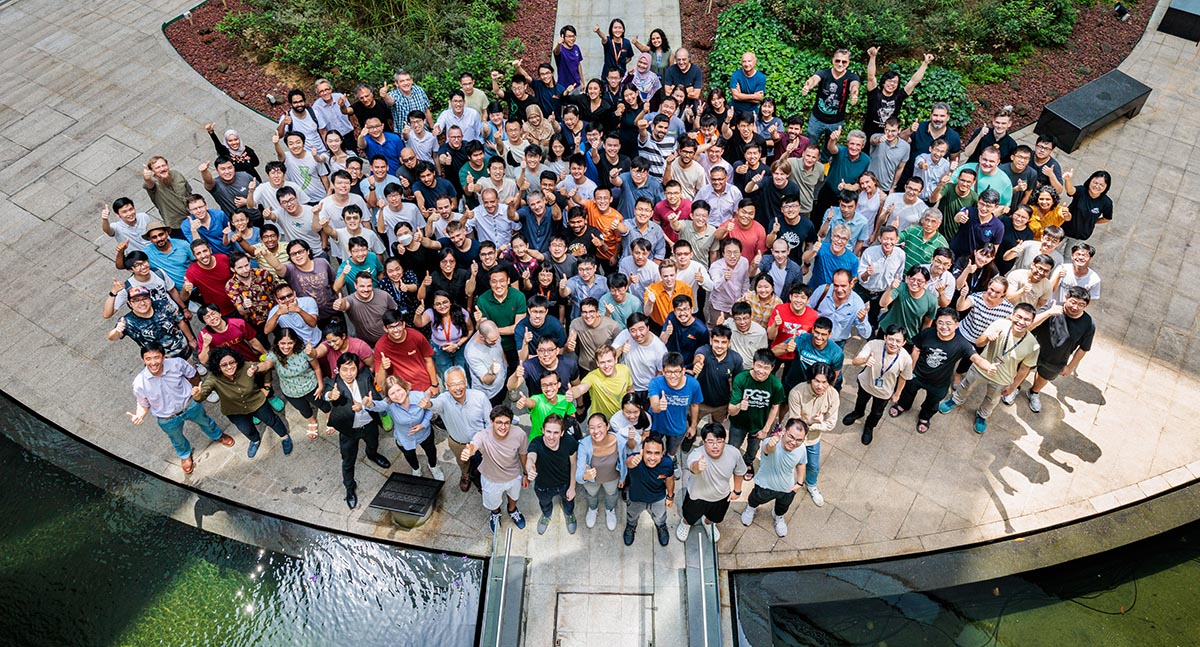 Group photo of CQT researchers, students and staff standing by a pond taken from above
